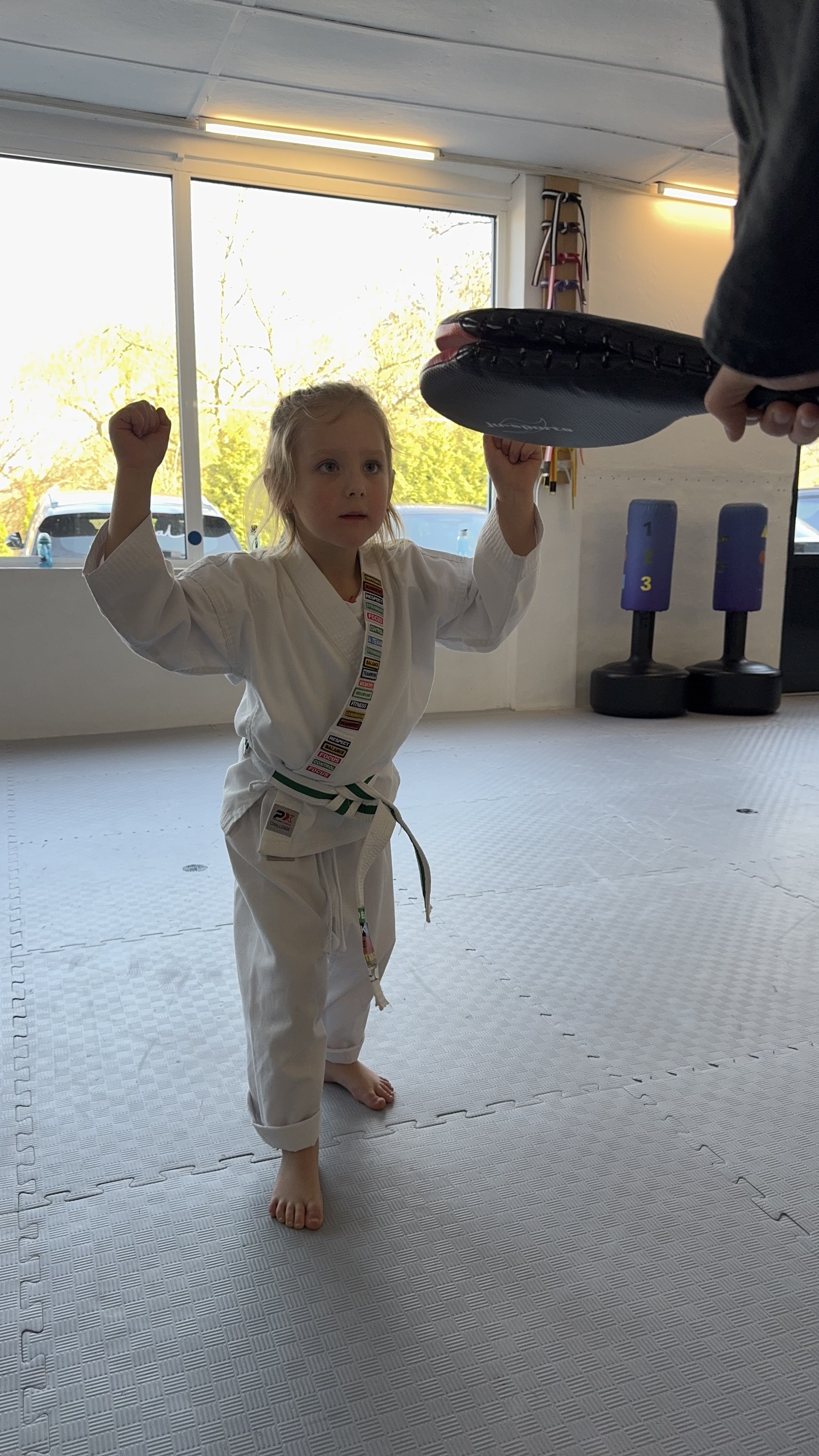 Kind im weißen Kampfkunstanzug im INSPIRE Dojo – konzentriert, selbstbewusst, mit Fäusten triumphierend